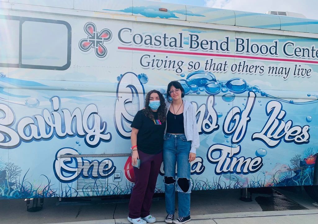 Two high school students in front of Coastal Bend Blood Mobile 