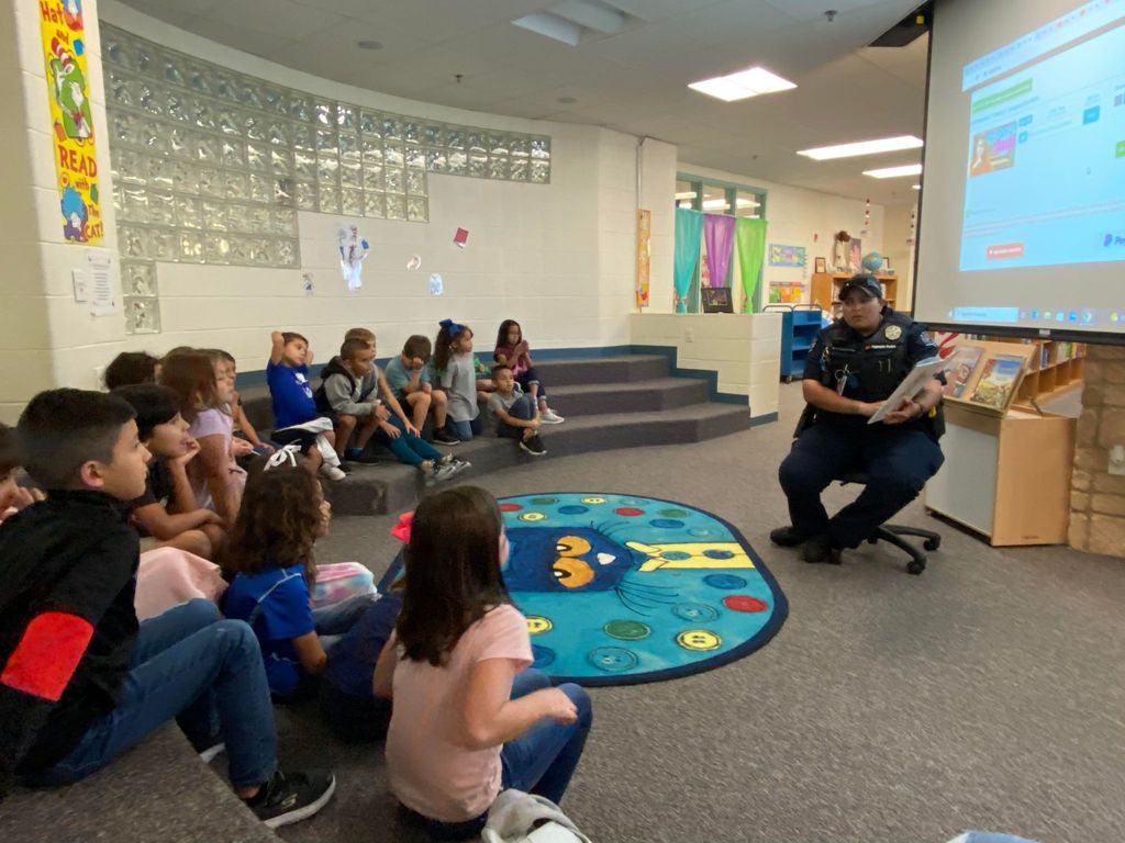 Officer reading to students in library